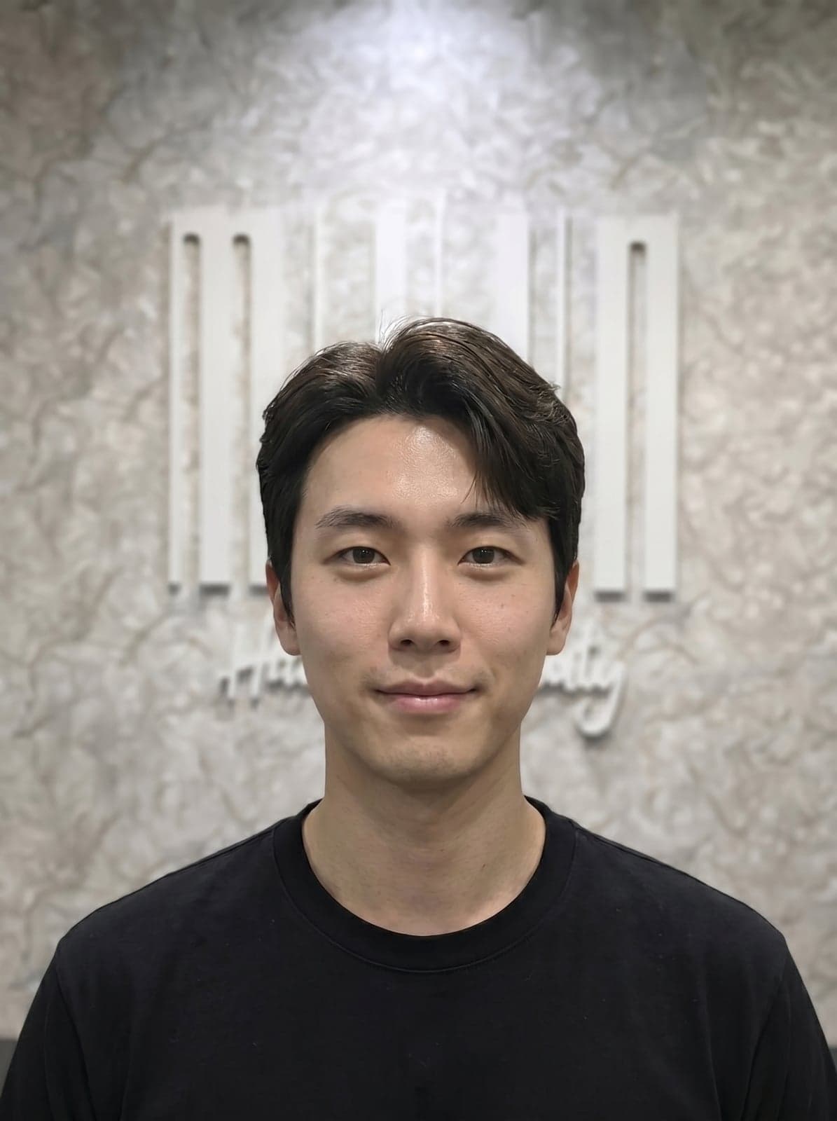 After down perm — same client, side hair now lying flat against the head, narrower polished silhouette