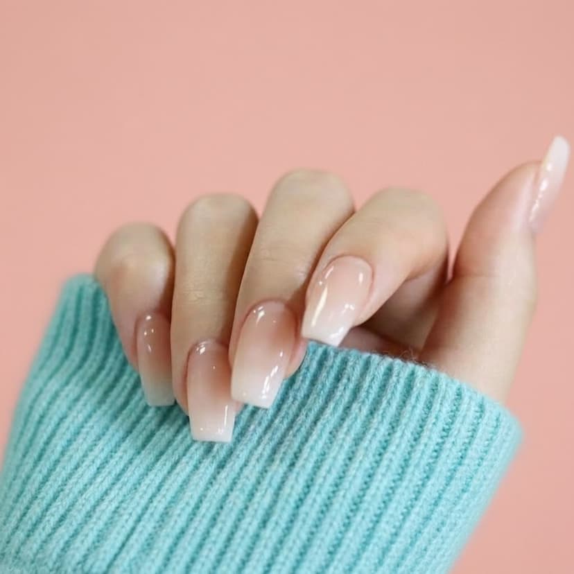 Nude gel nails on a hand with teal sleeve